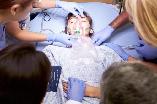 Person lying in hospital bed being resucitated