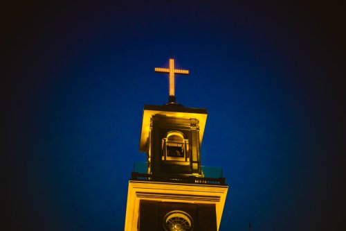 Church steeple lit up by lights at night