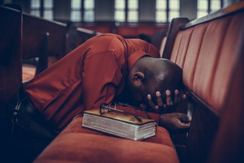 Man kneeling down and praying in a church