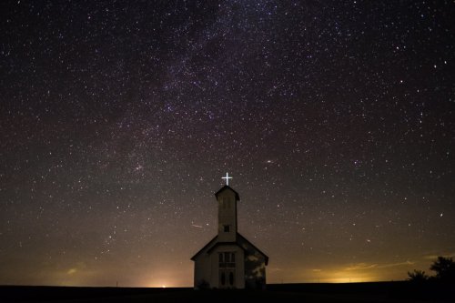 Night shot of a rural church, with a lit cross