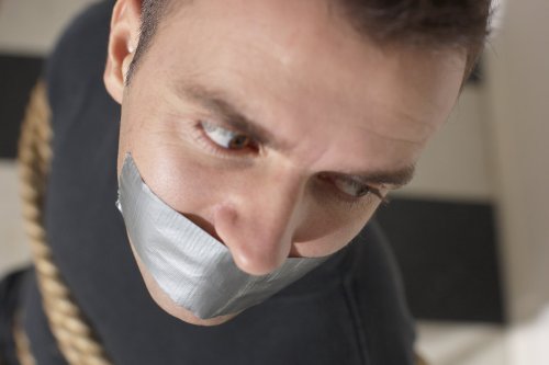 Man sitting in chair gagged and tied up with a rope