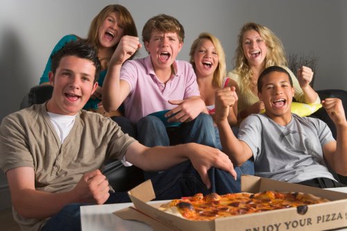 A group of teen boys and girls eating a pizza