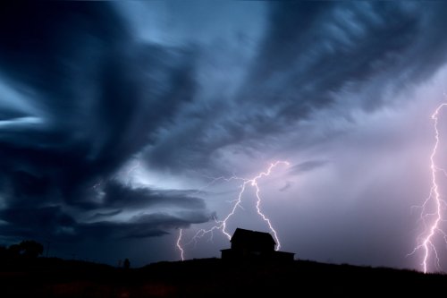 Storm clouds and lightening illuminating farmhouse