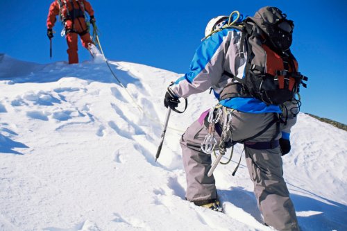 Young men mountain climbing on snowy peak
