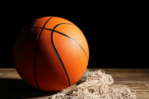 Ball for playing basketball and net on table against dark background