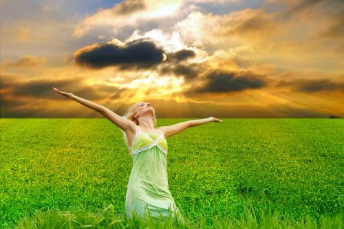 woman in a field with arms upraised