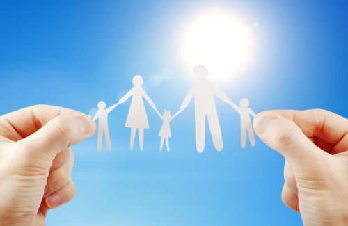 Person holding up a paper cut out of a family