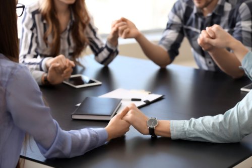 Group of people praying around a table