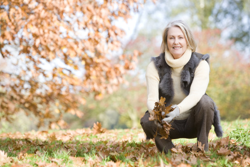 Senior woman collecting autumn leaves