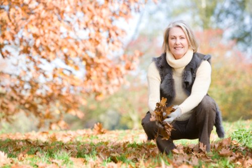 Senior woman collecting autumn leaves