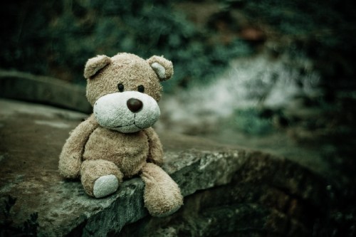 Teddy bear sitting on a cement bridge
