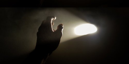 Hand in darkened room with a bright light in background