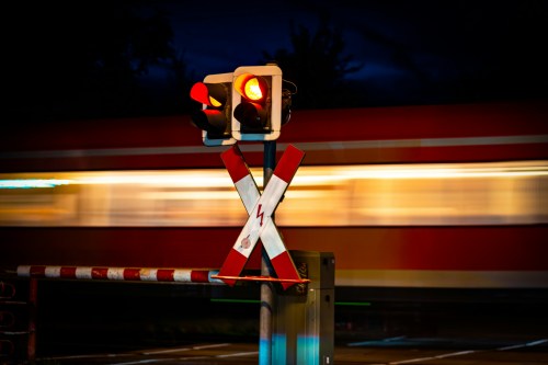 Train signal with train going past on the track at night